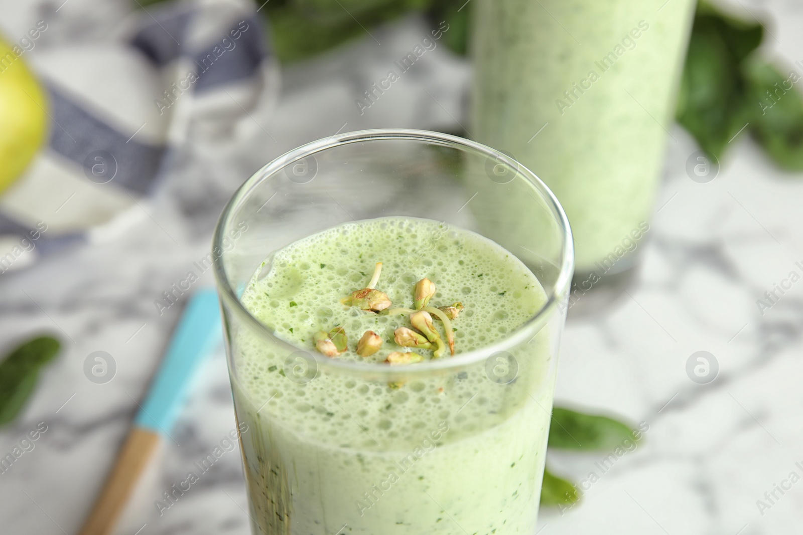 Photo of Green buckwheat smoothie on white marble table, closeup