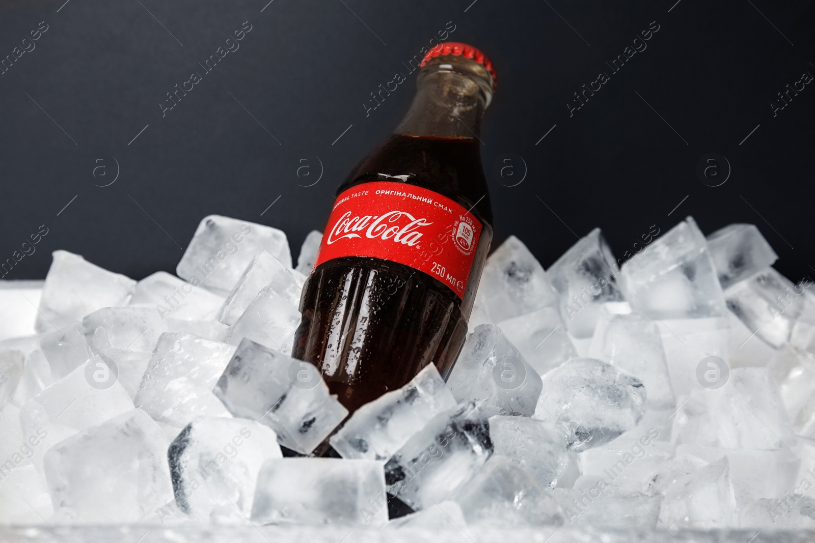 Photo of MYKOLAIV, UKRAINE - NOVEMBER 15, 2018: Bottle of Coca Cola on ice cubes against black background