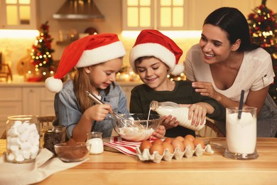 Photo of Happy mother and her children making dough for delicious Christmas cookies at home