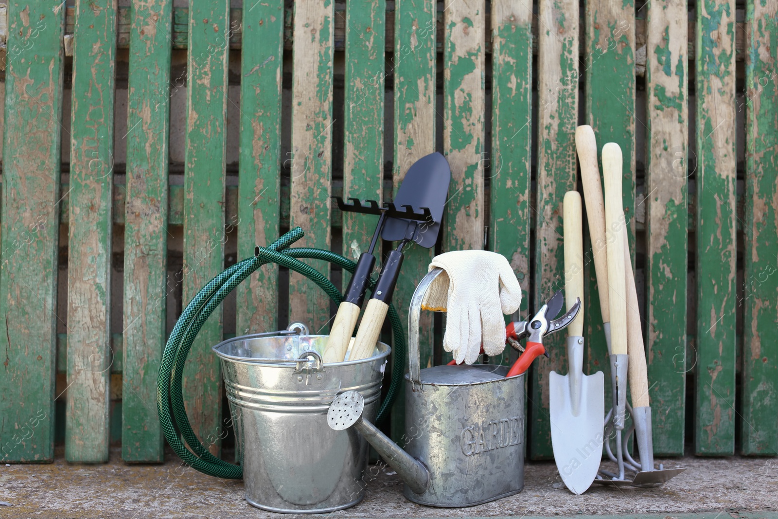 Photo of Set of gardening tools near wooden fence