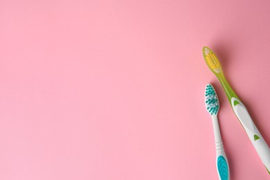 Photo of Toothbrushes on pink background, flat lay. Space for text