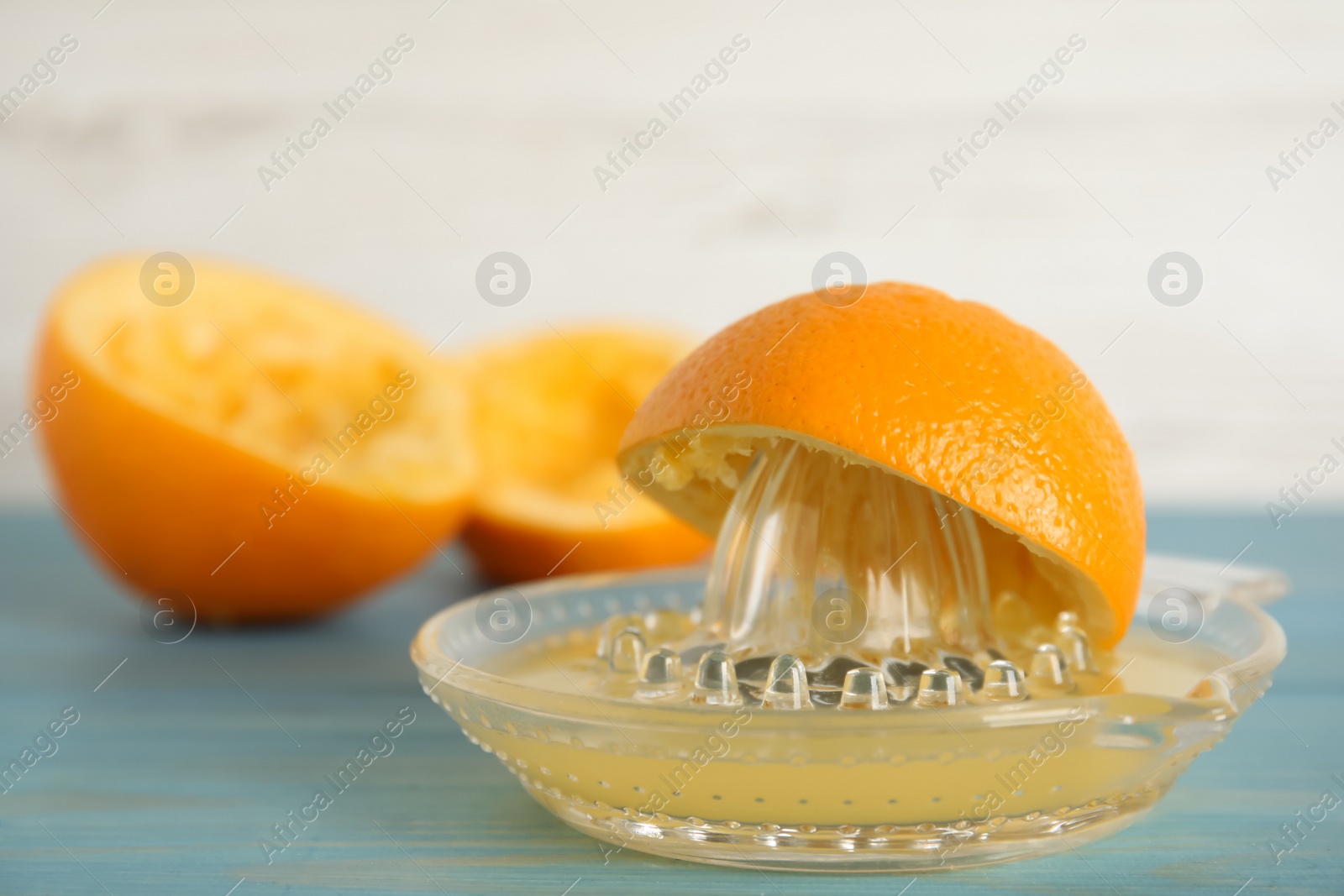 Photo of Cut fresh orange and squeezer on blue wooden table, closeup. Space for text