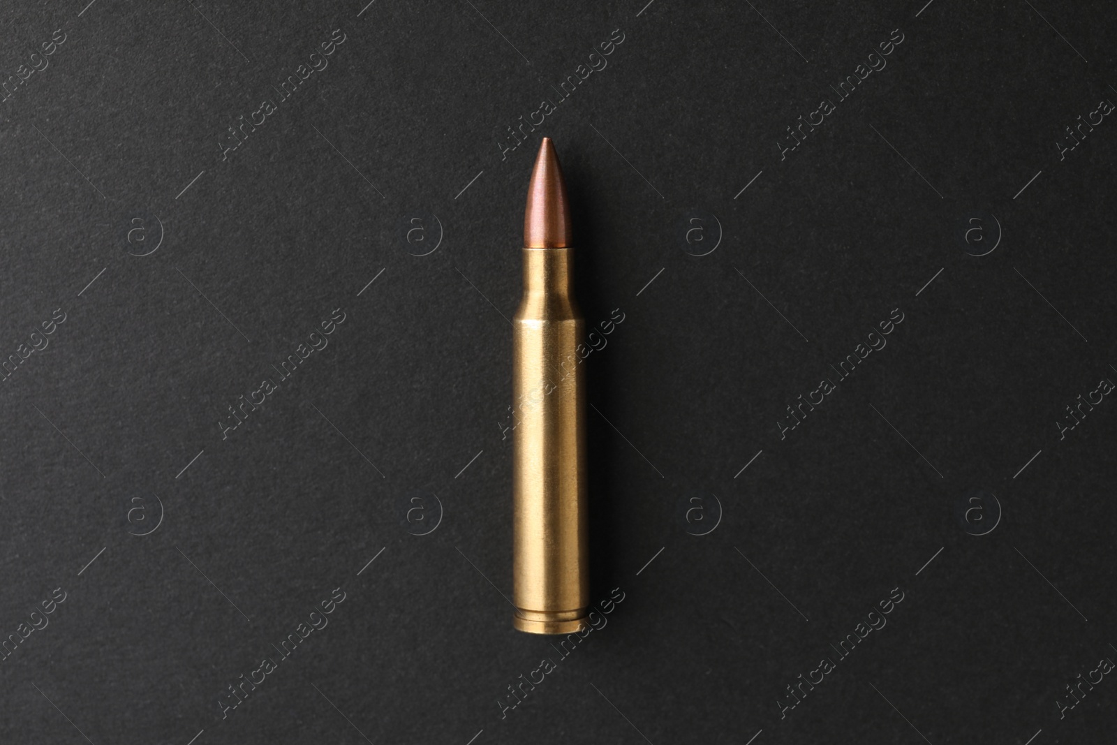Photo of One bullet on black background, top view