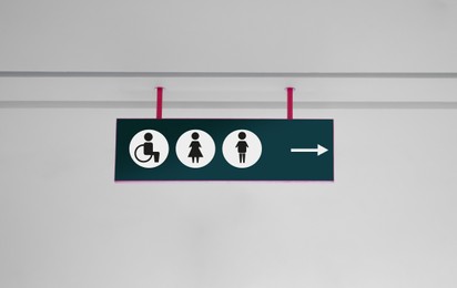 Public toilet sign with symbols and arrow showing direction