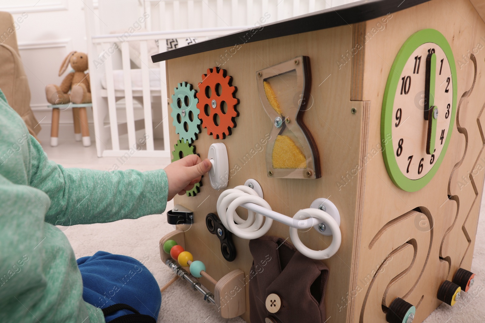 Photo of Little child playing with busy board house indoors, closeup