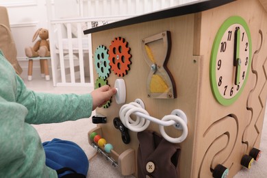 Photo of Little child playing with busy board house indoors, closeup