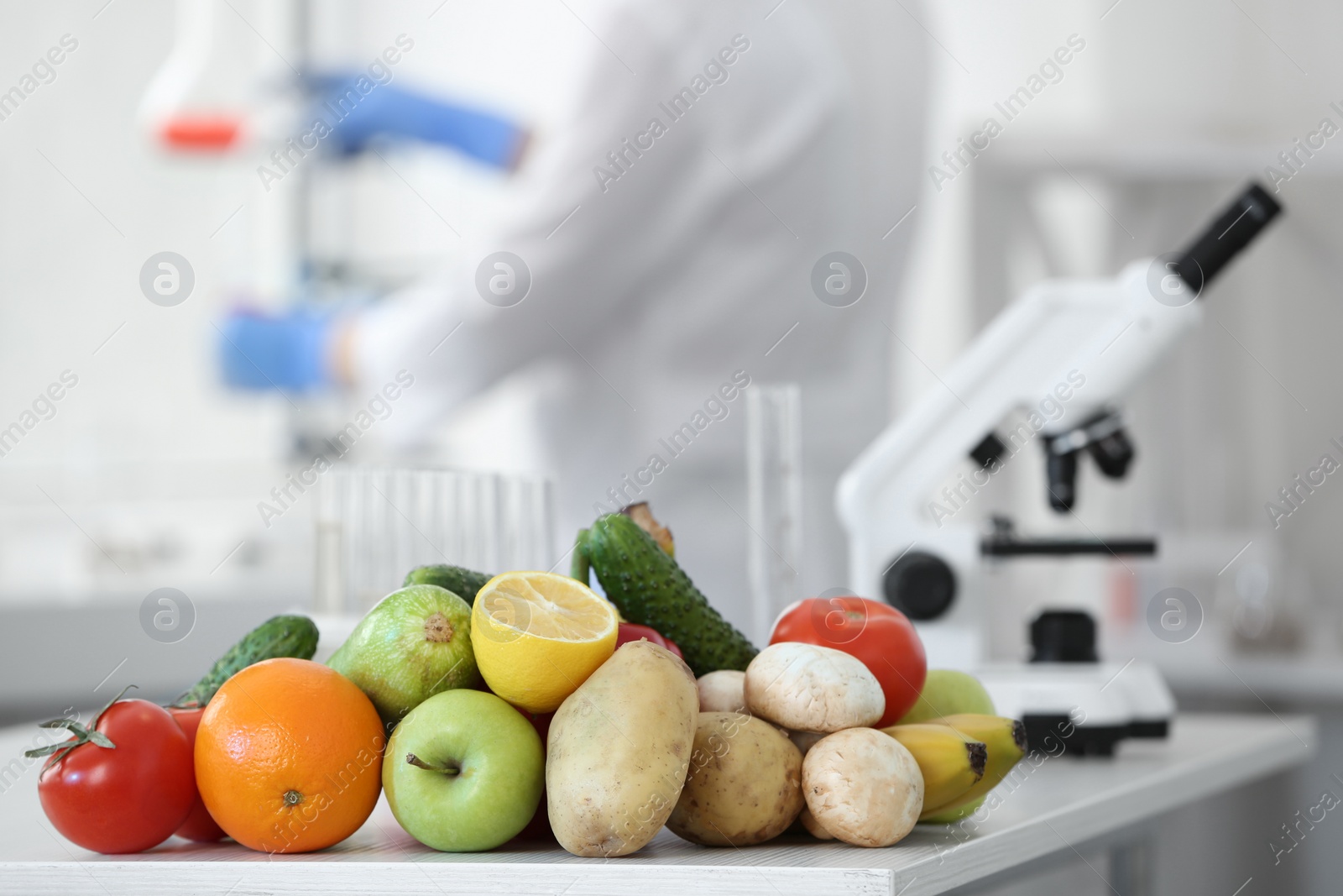 Photo of Fresh vegetables, fruits on table and scientist proceeding quality control in laboratory