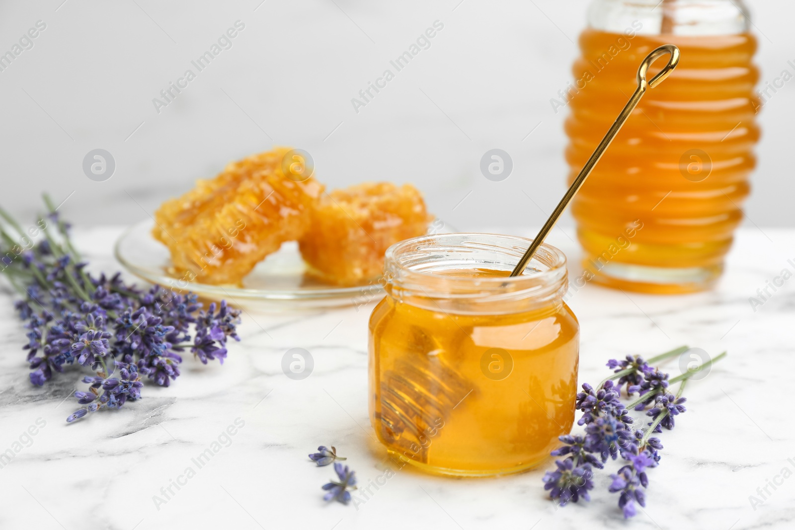 Photo of Tasty honey and lavender flowers on white marble table