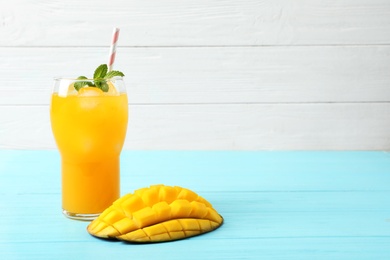 Fresh mango drink and cut fruit on blue wooden table. Space for text