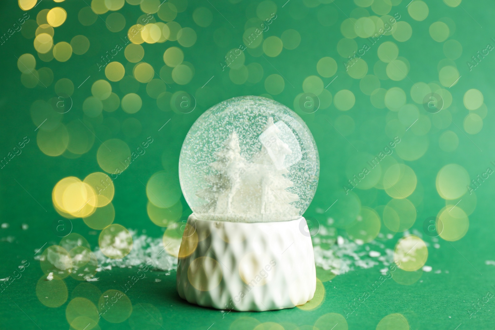 Image of Beautiful Christmas snow globe on green background, bokeh effect