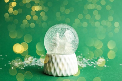 Image of Beautiful Christmas snow globe on green background, bokeh effect