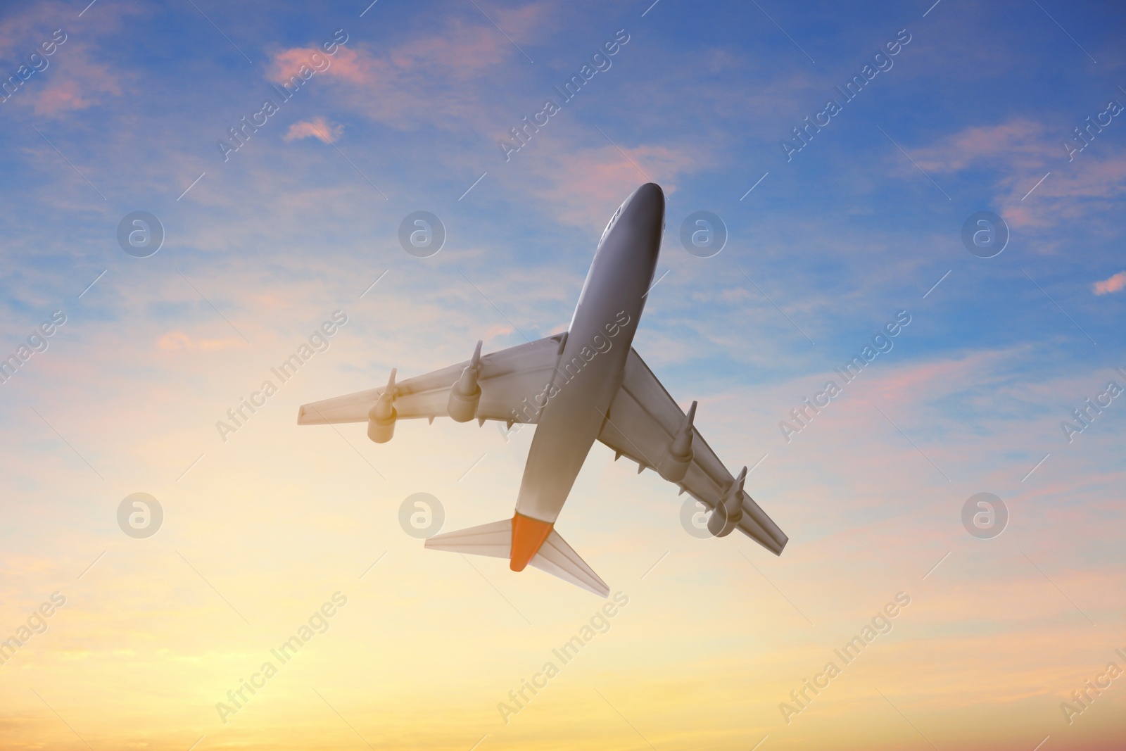Image of Airplane flying in cloudy sky at sunset. Air transportation