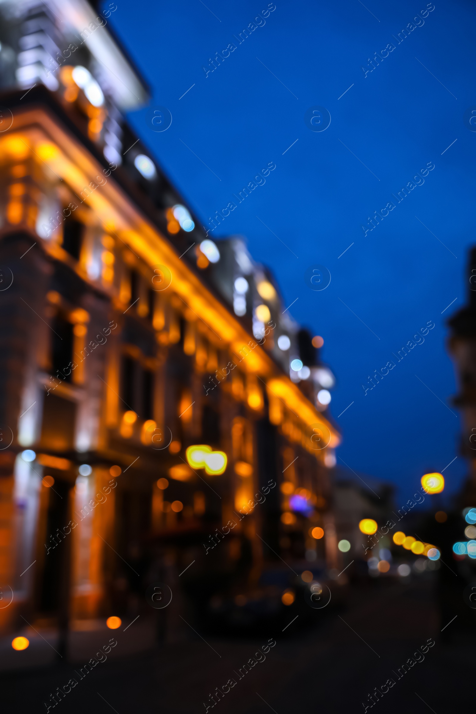 Photo of Blurred view of beautiful cityscape with glowing streetlights and illuminated building in evening