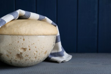 Photo of Bowl of fresh yeast dough on grey wooden table. Space for text