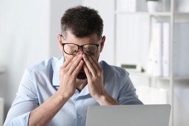Photo of Man suffering from eyestrain at workplace in office