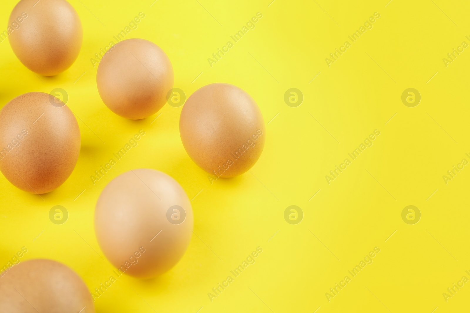 Photo of Raw brown chicken eggs on yellow background