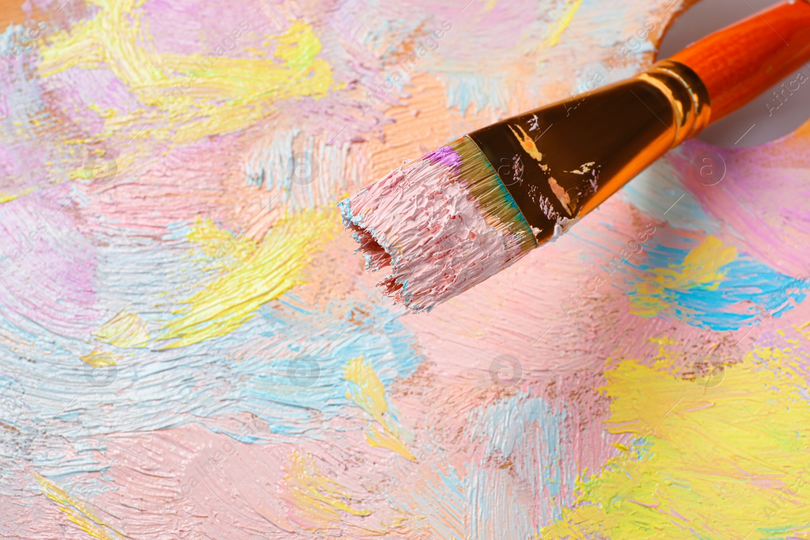 Photo of Closeup view of artist's palette with mixed pastel paints and brush as background