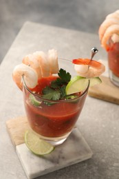 Photo of Tasty shrimp cocktail with sauce in glasses and lime on light grey table, closeup