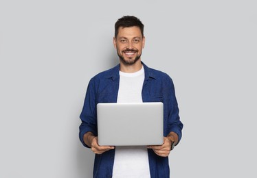 Smiling man with laptop on light grey background