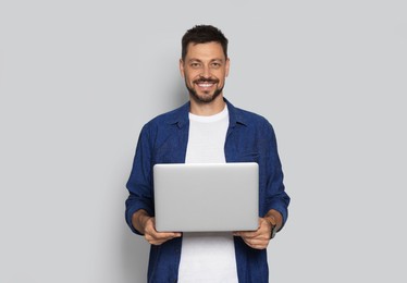 Photo of Smiling man with laptop on light grey background