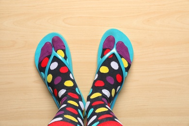 Photo of Woman wearing bright socks with flip-flops standing on floor, top view