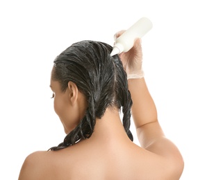 Young woman dyeing her hair against white background, back view