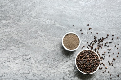 Photo of Ground black pepper and corns on grey table, top view. Space for text