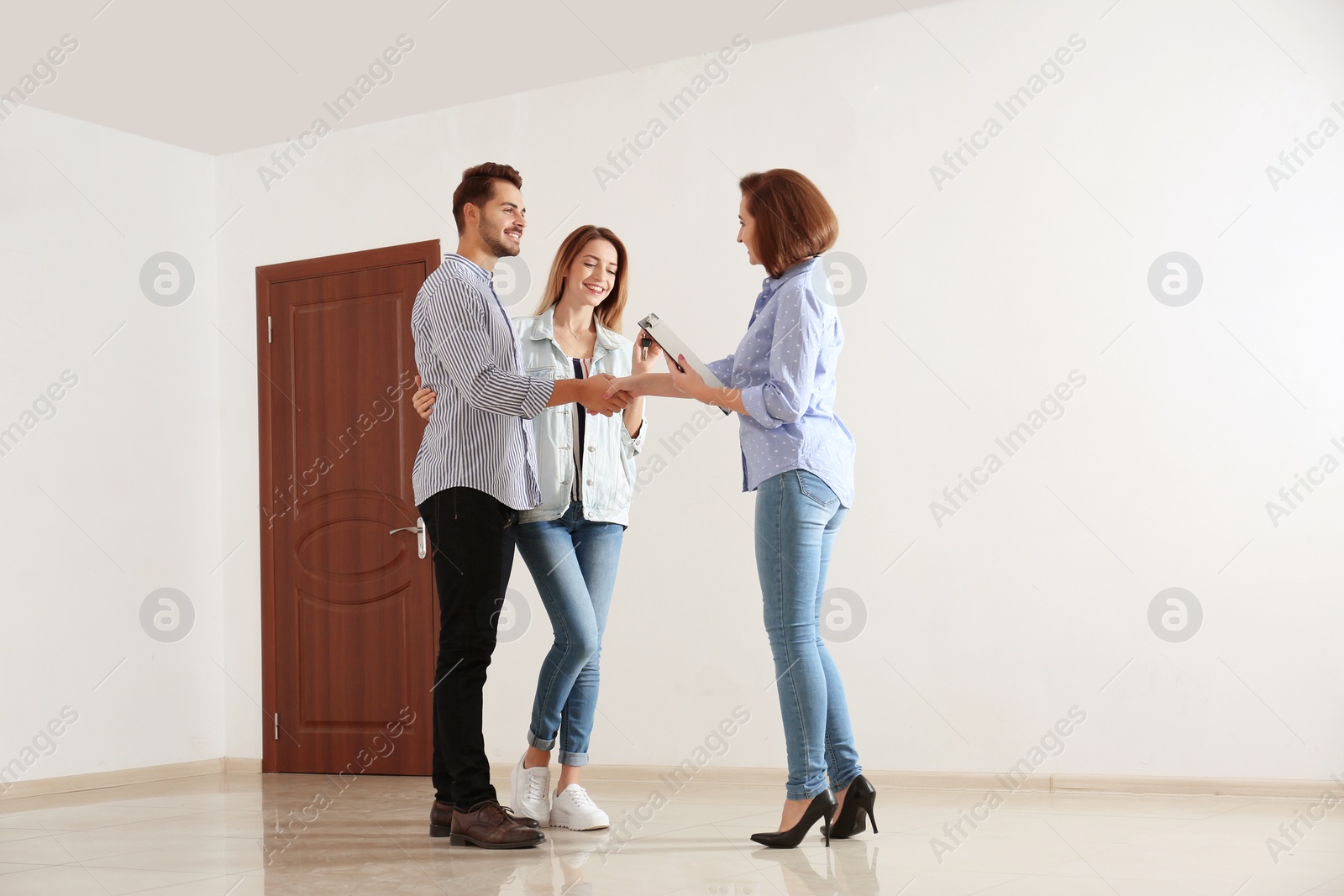 Photo of Real estate agent with young couple in new apartment
