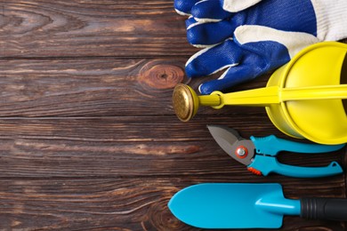 Photo of Flat lay composition with watering can and gardening tools on wooden table. Space for text