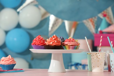 Photo of Different colorful cupcakes and party accessories on pink table