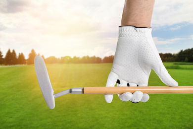 Image of Player holding golf club in park on sunny day, closeup