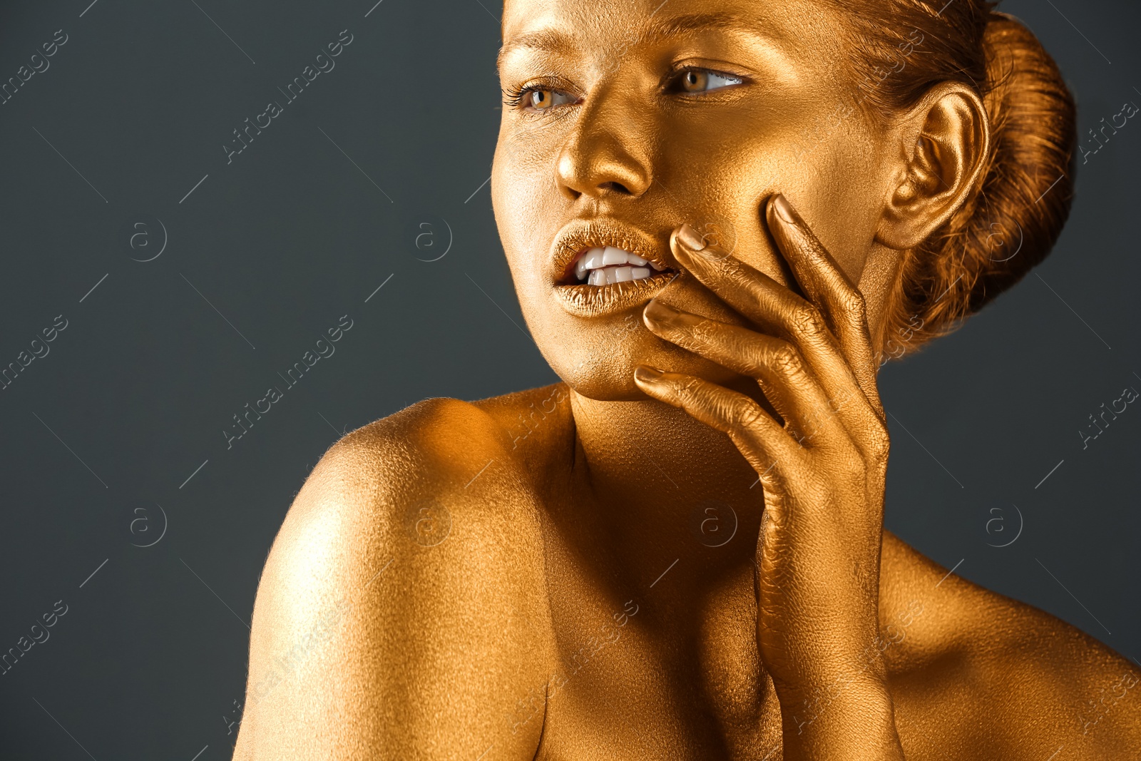 Photo of Portrait of beautiful lady with gold paint on skin against grey background, closeup