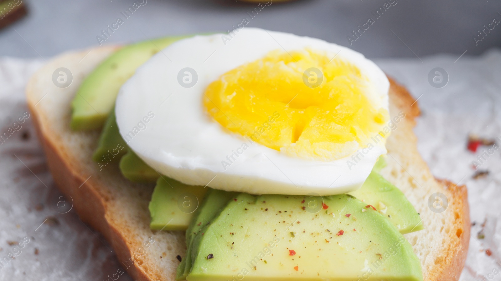 Photo of Delicious sandwich with boiled egg and pieces of avocado on table, closeup