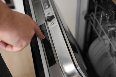 Photo of Man pushing button on dishwasher's door indoors, closeup