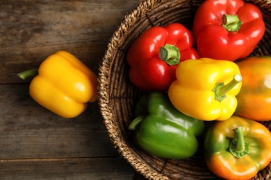 Photo of Bowl with ripe paprika peppers on wooden background, top view