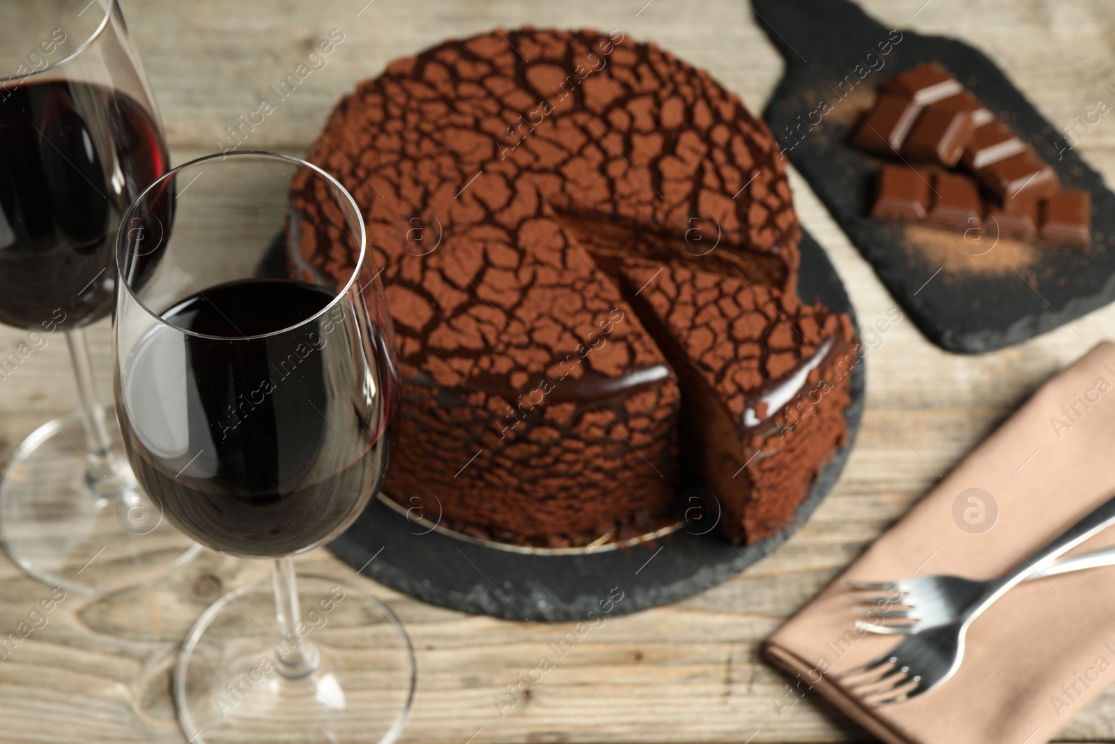 Photo of Delicious chocolate truffle cake and red wine on wooden table