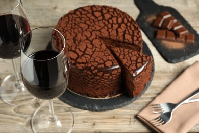 Photo of Delicious chocolate truffle cake and red wine on wooden table