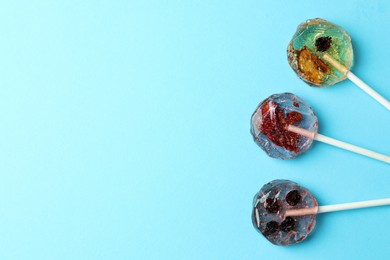 Photo of Sweet colorful lollipops with berries on light blue background, flat lay. Space for text