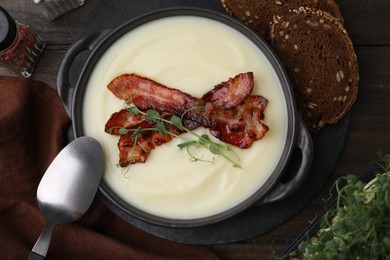 Photo of Delicious potato soup with bacon and microgreens in bowl served on wooden table, flat lay