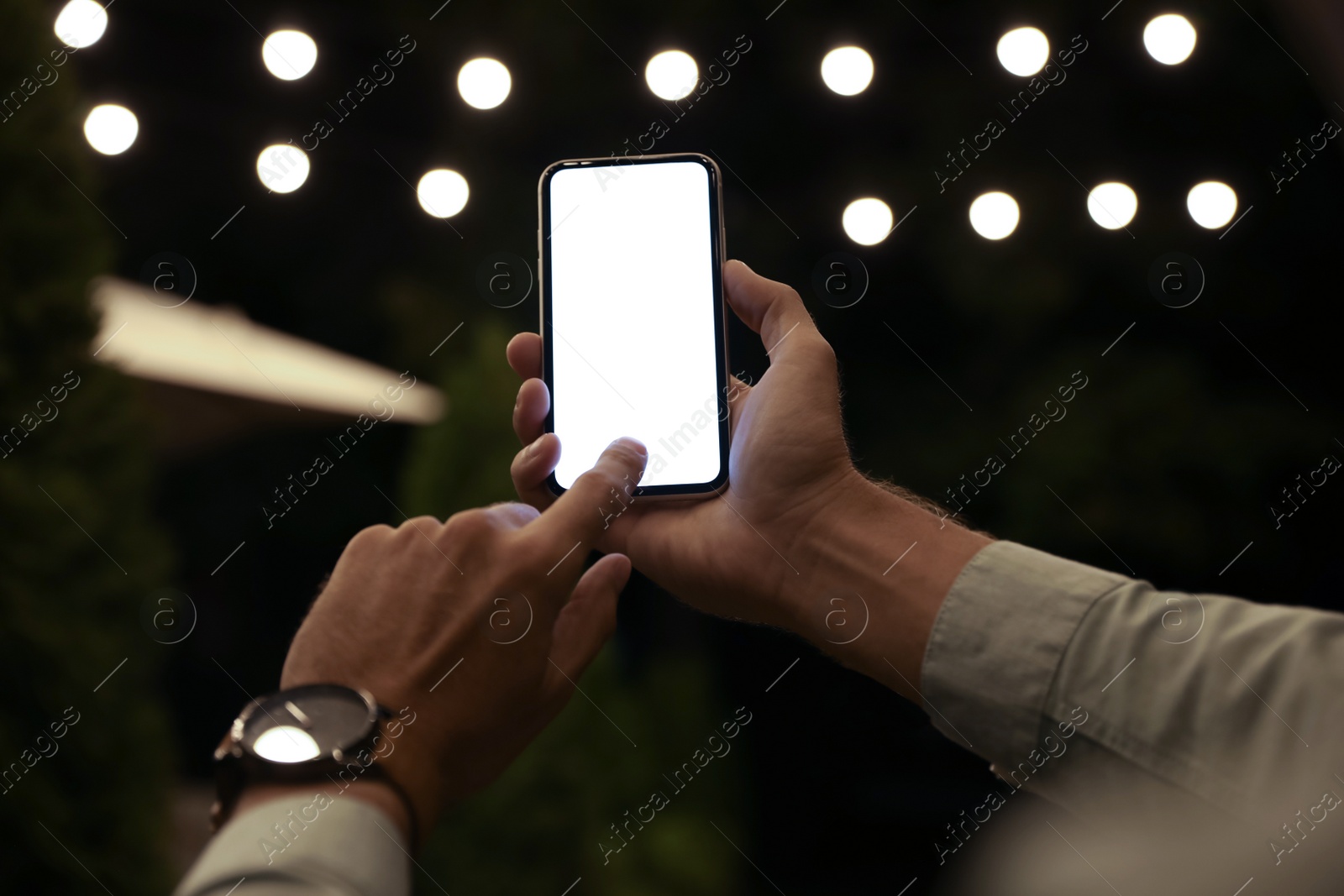 Photo of Man using modern mobile phone outdoors at night, closeup