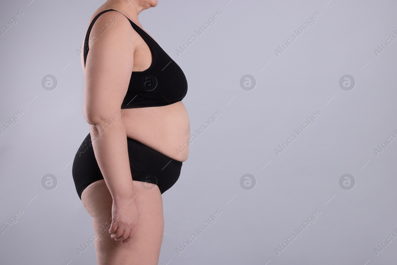 Photo of Overweight woman in underwear on grey background, closeup. Space for text