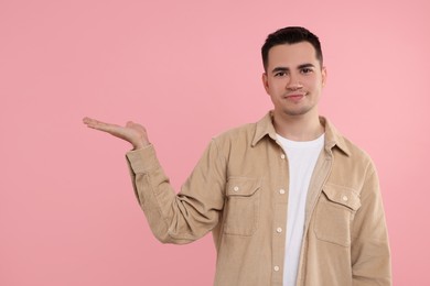 Photo of Special promotion. Young man showing something on pink background, space for text