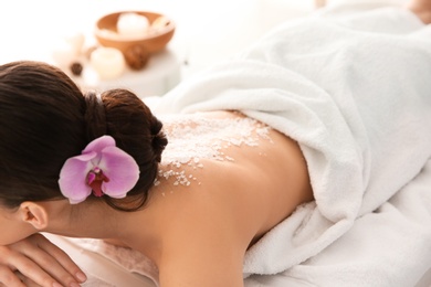 Photo of Beautiful young woman with body scrub on her back in spa salon