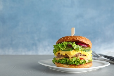 Photo of Plate with tasty burger on table against color background. Space for text