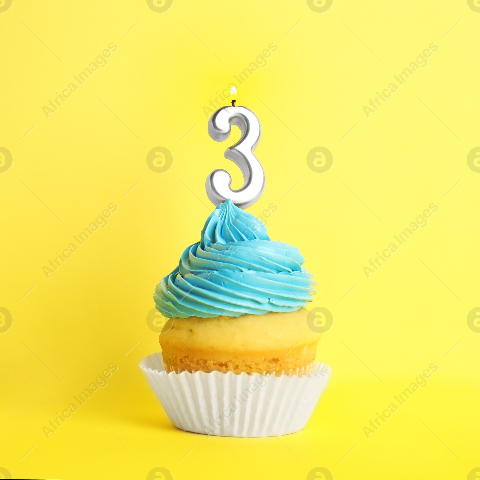 Photo of Birthday cupcake with number three candle on yellow background