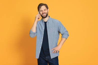 Man talking on smartphone against orange background