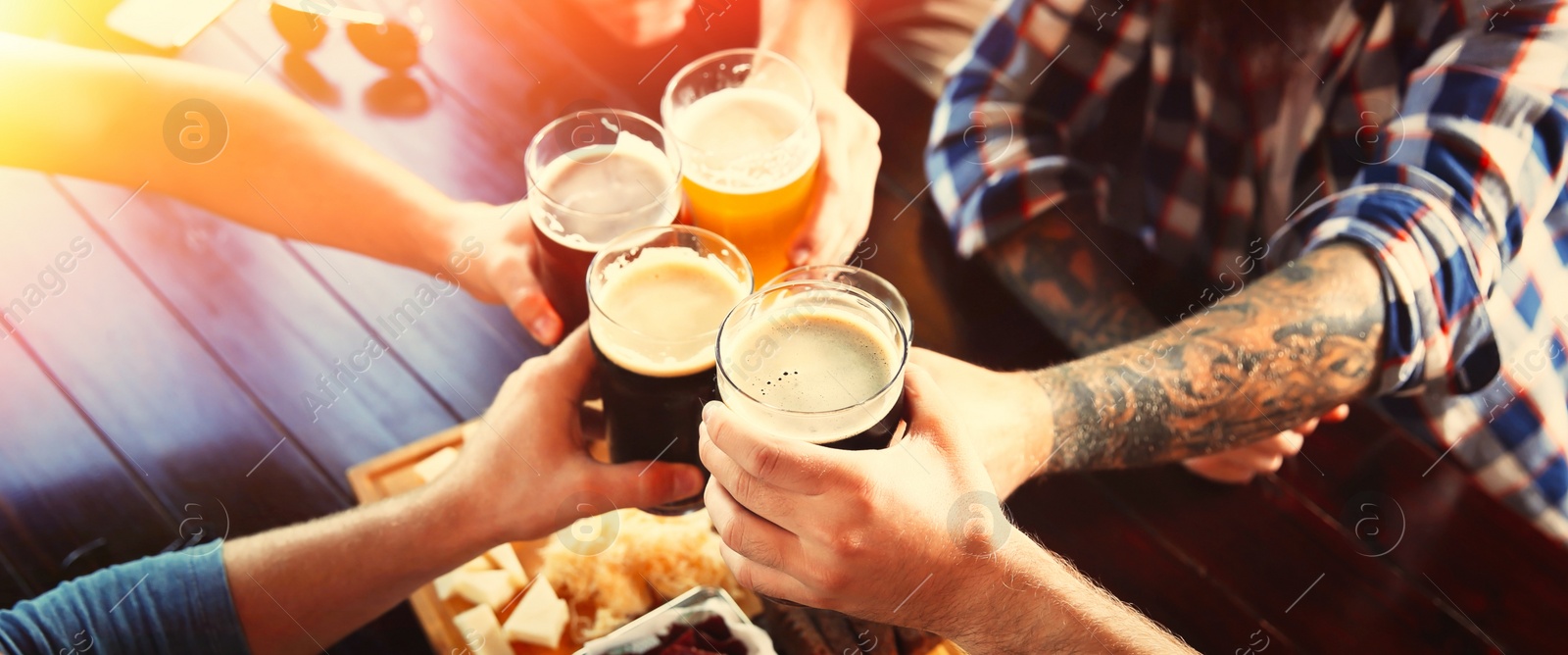 Image of Group of friends toasting with beer in pub, closeup. Banner design