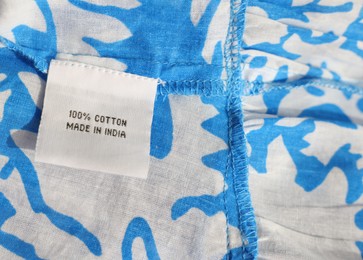 Clothing label on color garment, closeup view