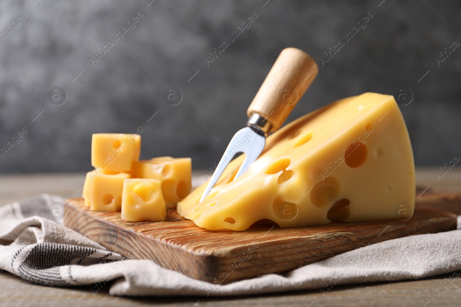 Photo of Tasty fresh cheese with fork on wooden table, closeup