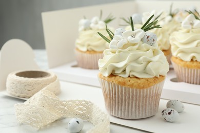 Photo of Tasty Easter cupcakes with vanilla cream on white marble table